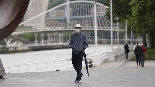 Una persona pasea por Bilbao protegido con una mascarilla