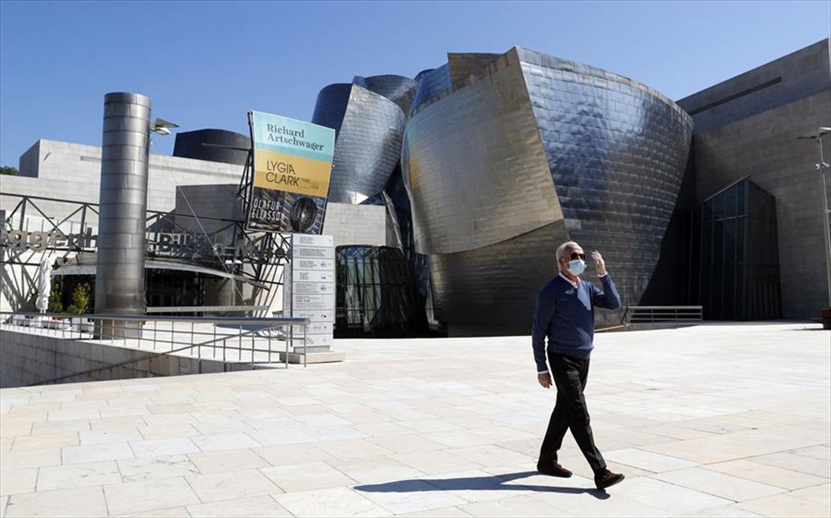 Gizon bat Guggenheim Bilbao Museoaren ondoan paseatzen.