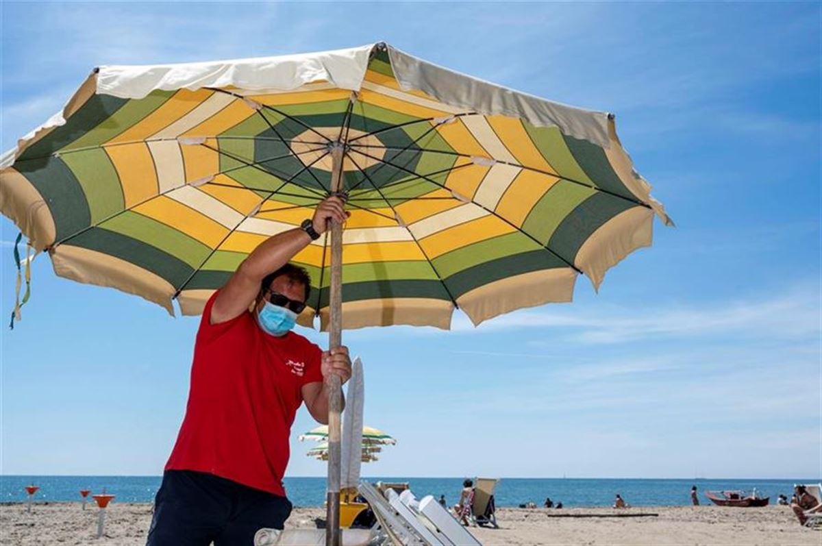 Un hombre abre una sombrilla en la playa. Foto: Efe