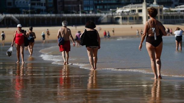 Varias personas caminando por la orilla de la Playa de La Concha