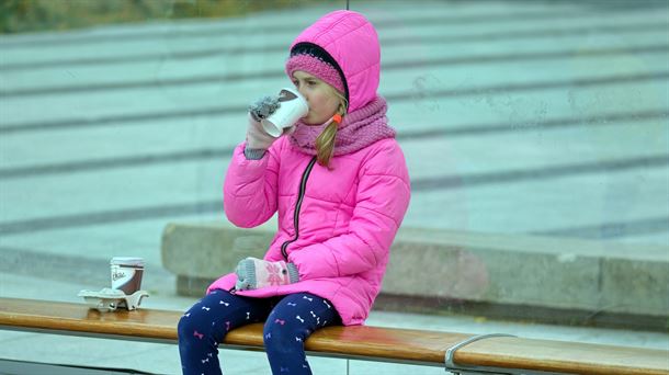 Una niña bebiendo de un vaso de plástico