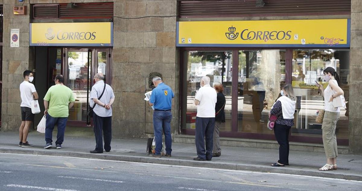 Varias personas en Bilbao esperando para depositar su voto por correo. 