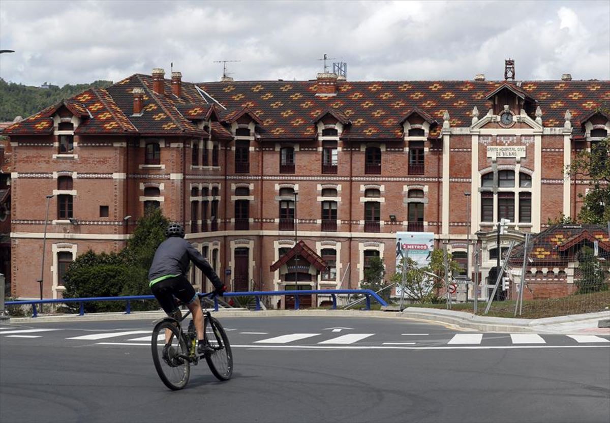 Una persona en una bicicleta frente al Hospital de Basurto.