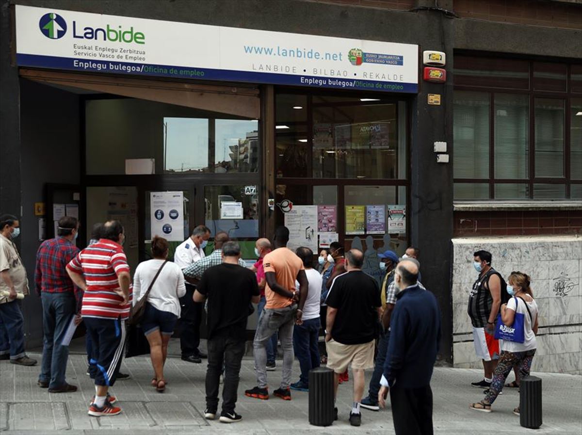 Un grupo de personas haciendo cola para entrar a una oficina de Lanbide