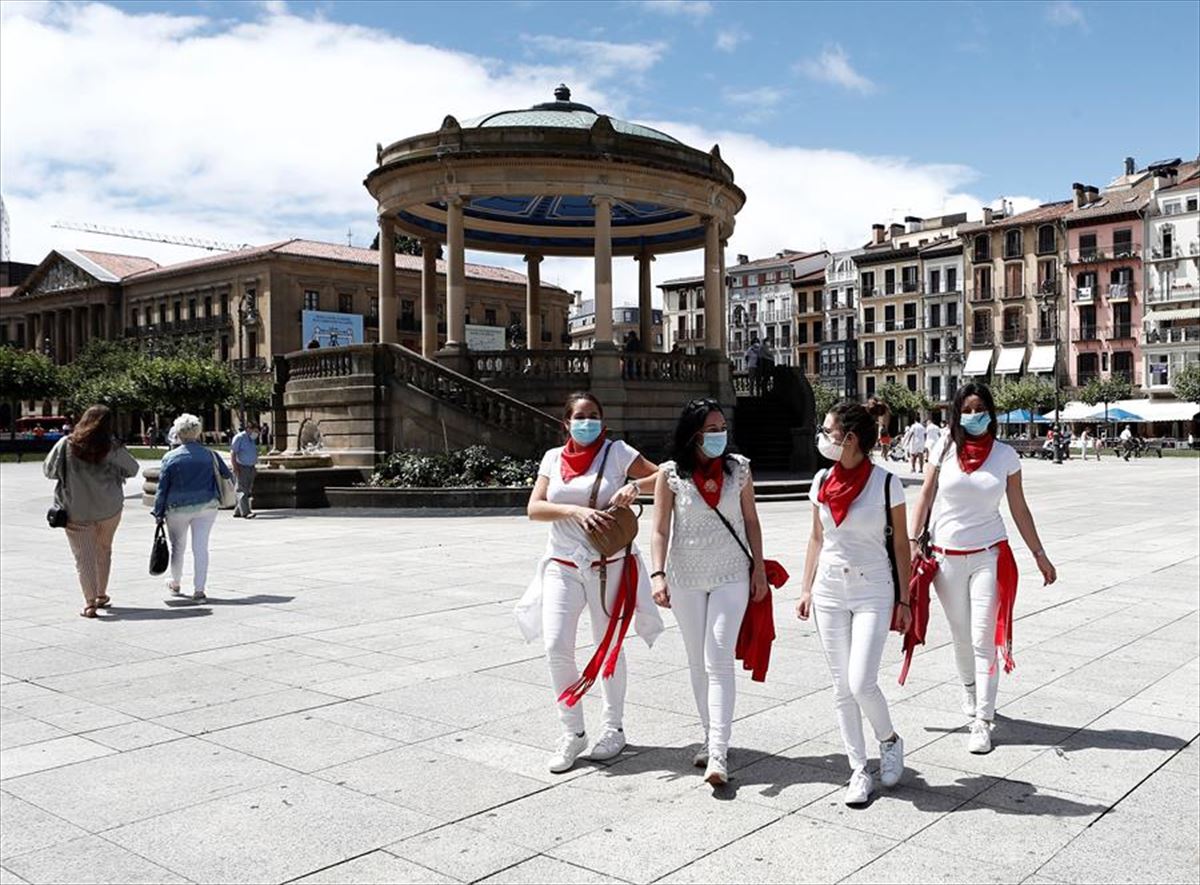Cuatro personas con la vestimenta típica de los Sanfermines, en la Plaza del Castillo. 