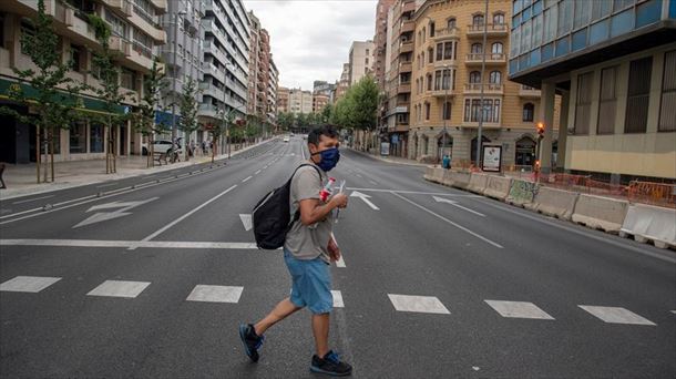 Un hombre con mascarilla cruza una avenida vacía en Lleida.