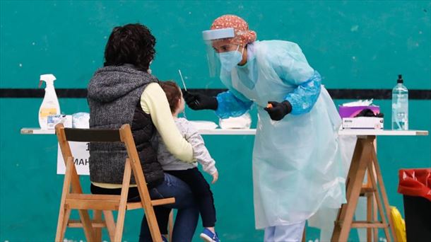 Una profesional sanitaria realiza una prueba PCR a un menor.