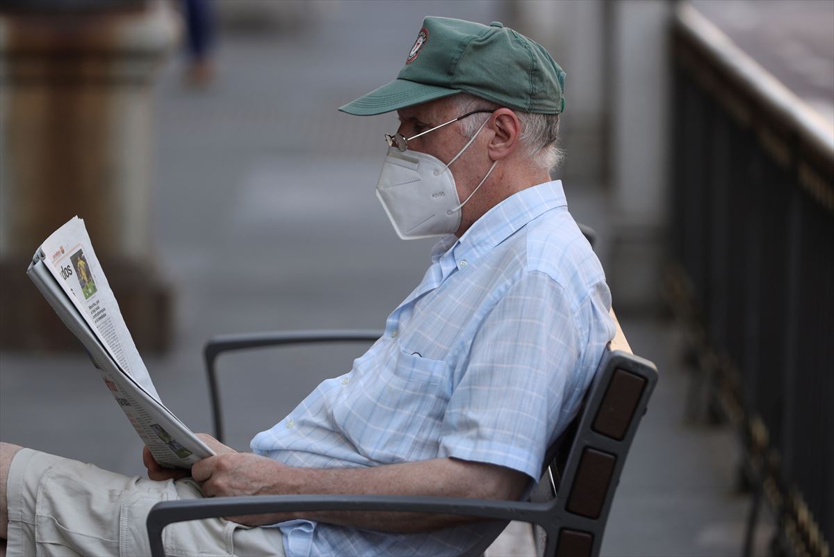 Hombre leyendo el periódico en la calle con mascarilla. Foto: Efe