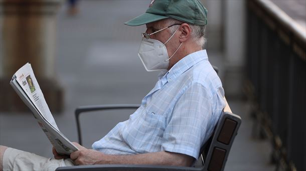 Hombre leyendo el periódico en la calle con mascarilla. Foto: Efe