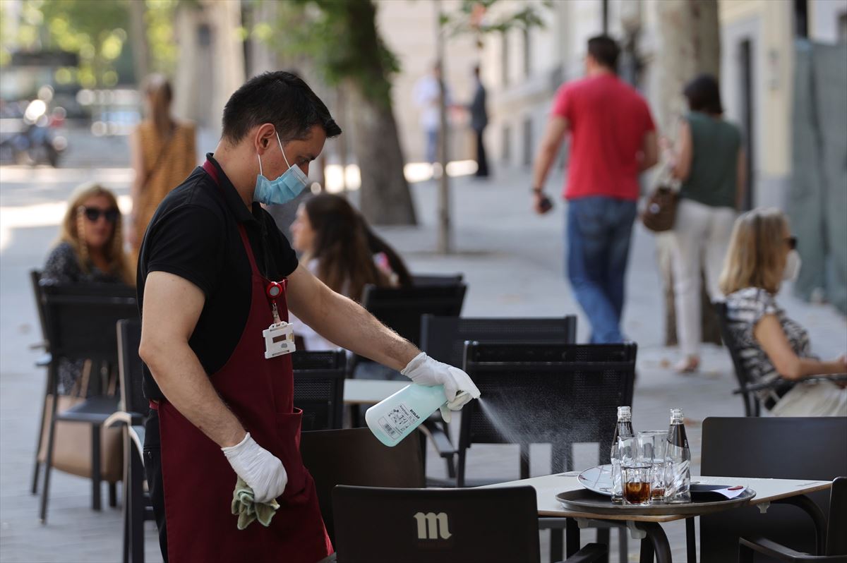Un camarero desinfecta la mesa de una terraza. Foto: EFE