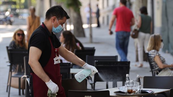 Zerbitzari bat terraza bateko mahaia garbitzen. Argazkia: EFE