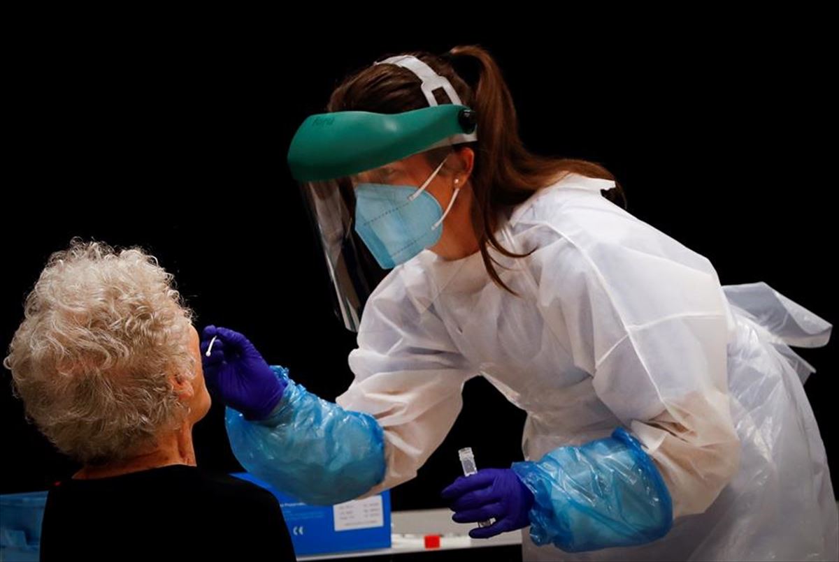 Una profesional sanitaria realiza una prueba PCR a una persona mayor.