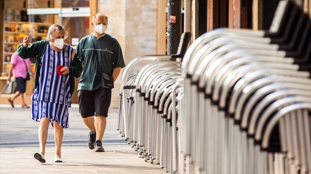 Dos personas caminan por la calle con mascarilla