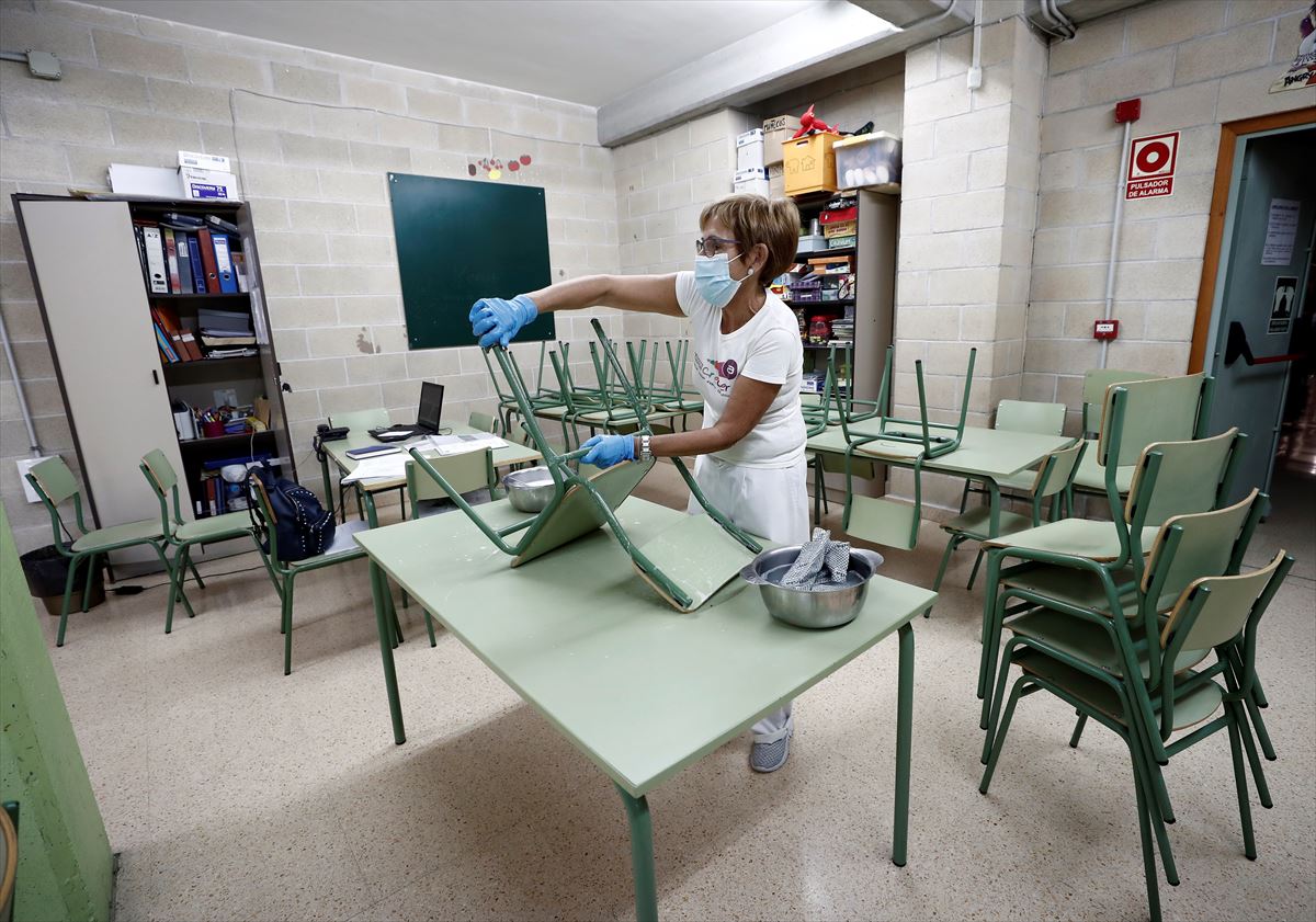 Una trabajadora de limpieza desinfecta una aula. 