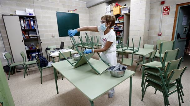 Una trabajadora de limpieza desinfecta una aula. 