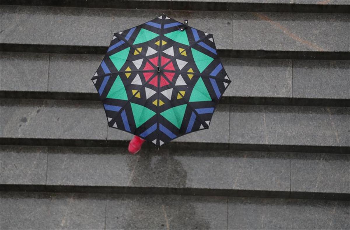 Una persona se resguarda de la lluvia bajo un paraguas. 