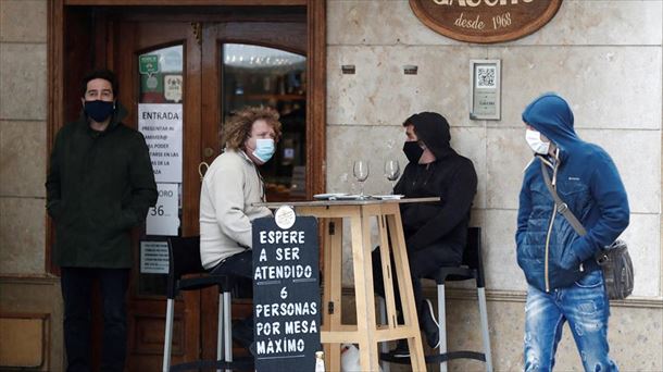 Hainbat pertsona terraza batean, musukoa jantzita. Artxiboko argazkia: EFE.