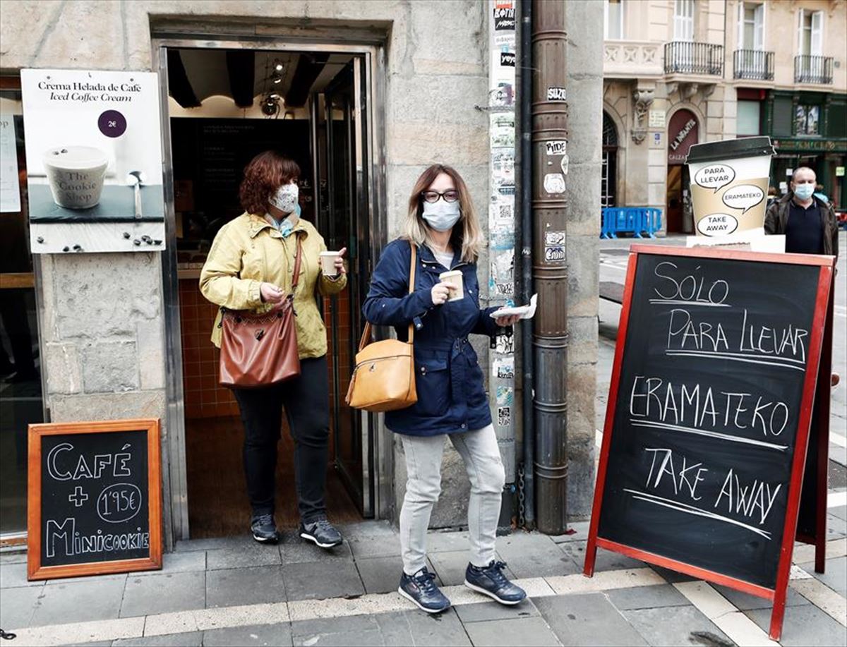 Dos mujeres salen con un cafe en la mano de un bar en Pamplona. Foto: EFE