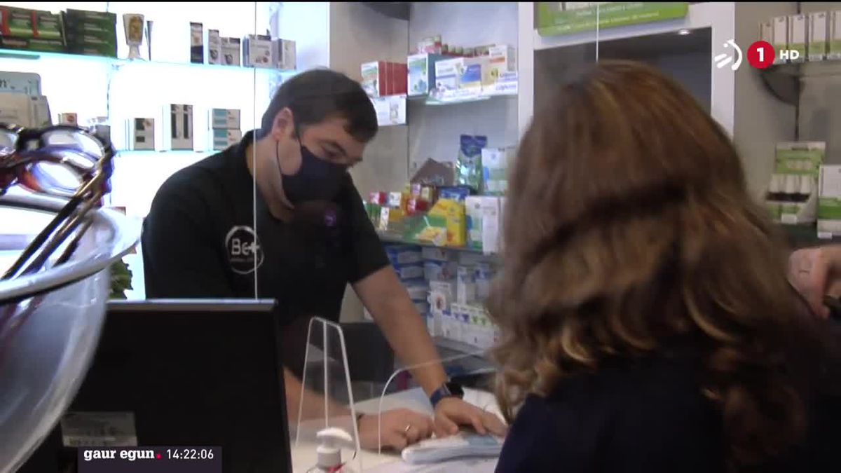 Una cliente compra una mascarilla en una farmacia.