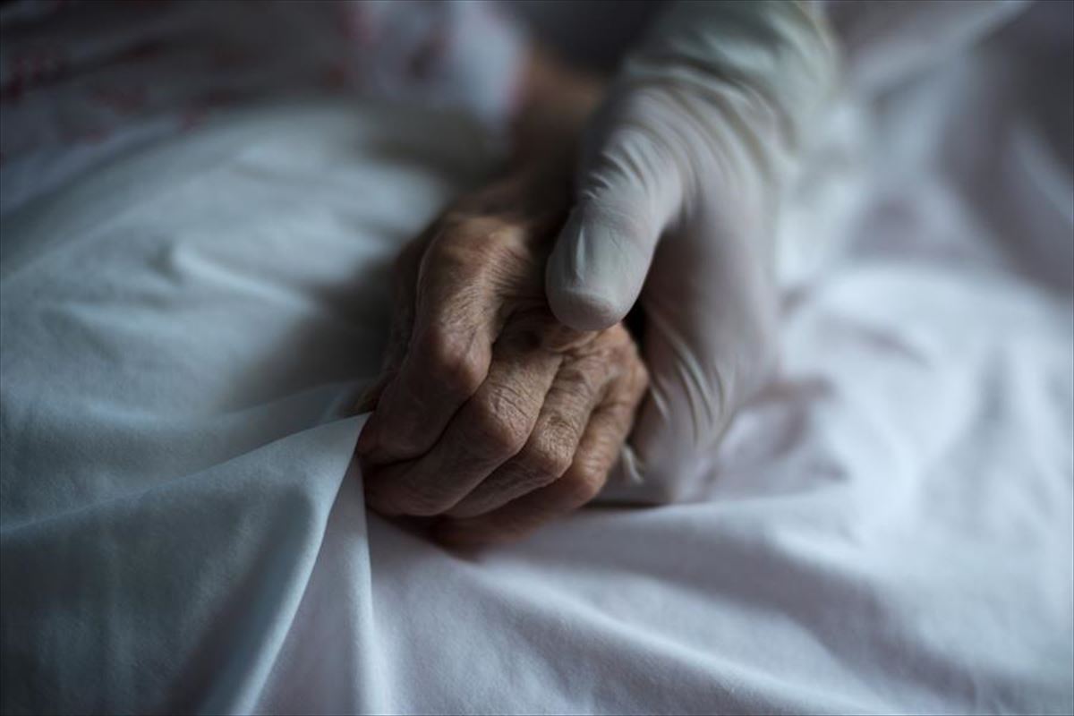 Personal sanitario agarra la mano a un paciente de covid