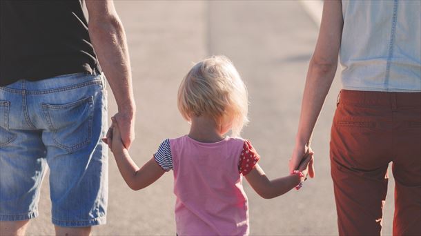 Un menor, de la mano de dos personas adultas