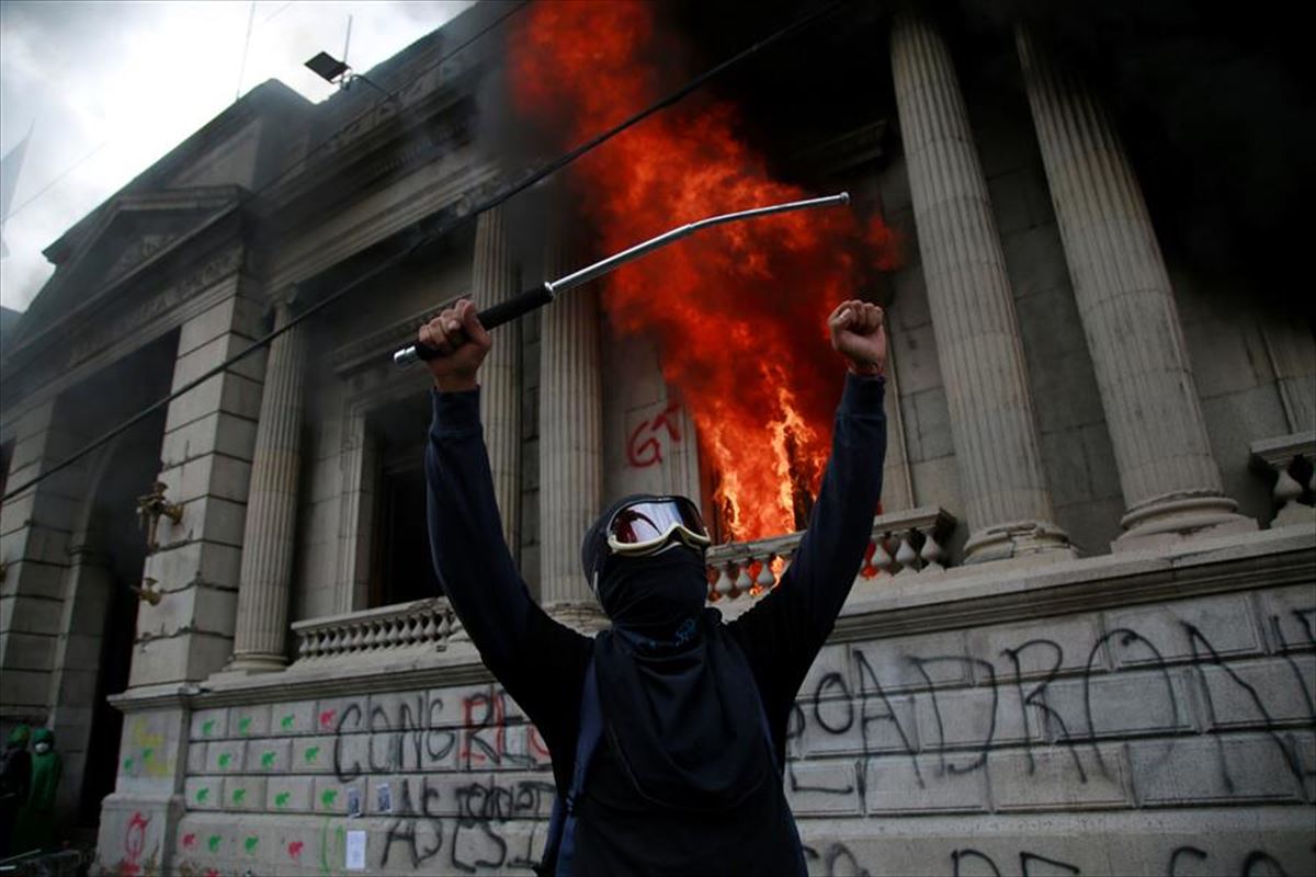 Un hombre protesta en frente del Congreso de Guatemala en llamas. Foto: EFE
