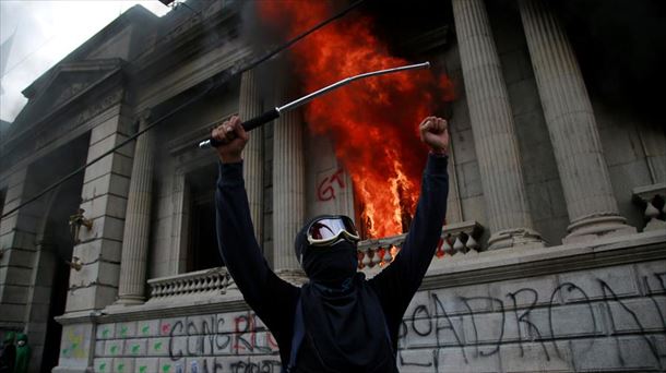 Un hombre protesta en frente del Congreso de Guatemala en llamas. Foto: EFE