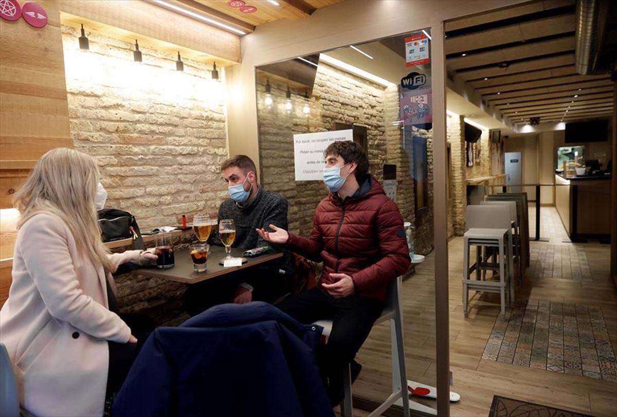 Varios clientes ocupan una mesa en un bar de Pamplona