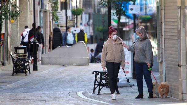 Dos mujeres pasean por la calles, con mascarillas.