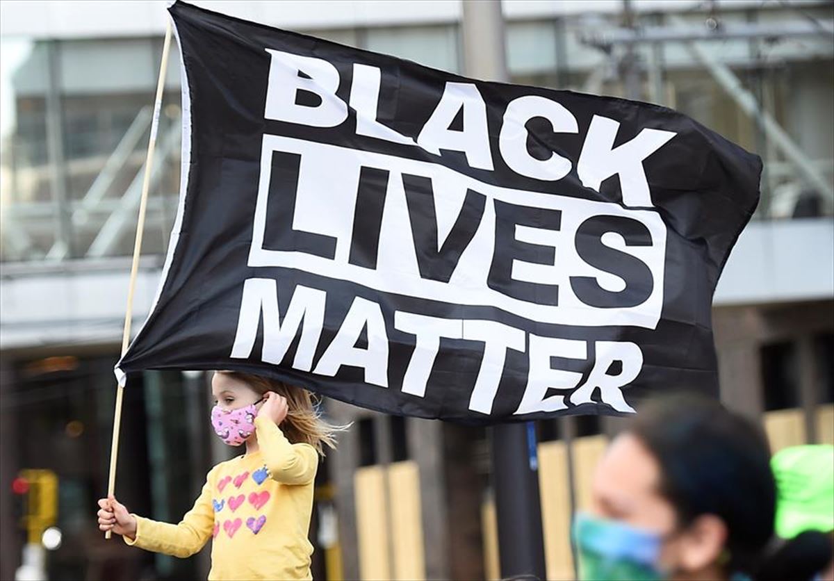 Niña portando una bandera del movimiento Black Lives Matter (BLM). 