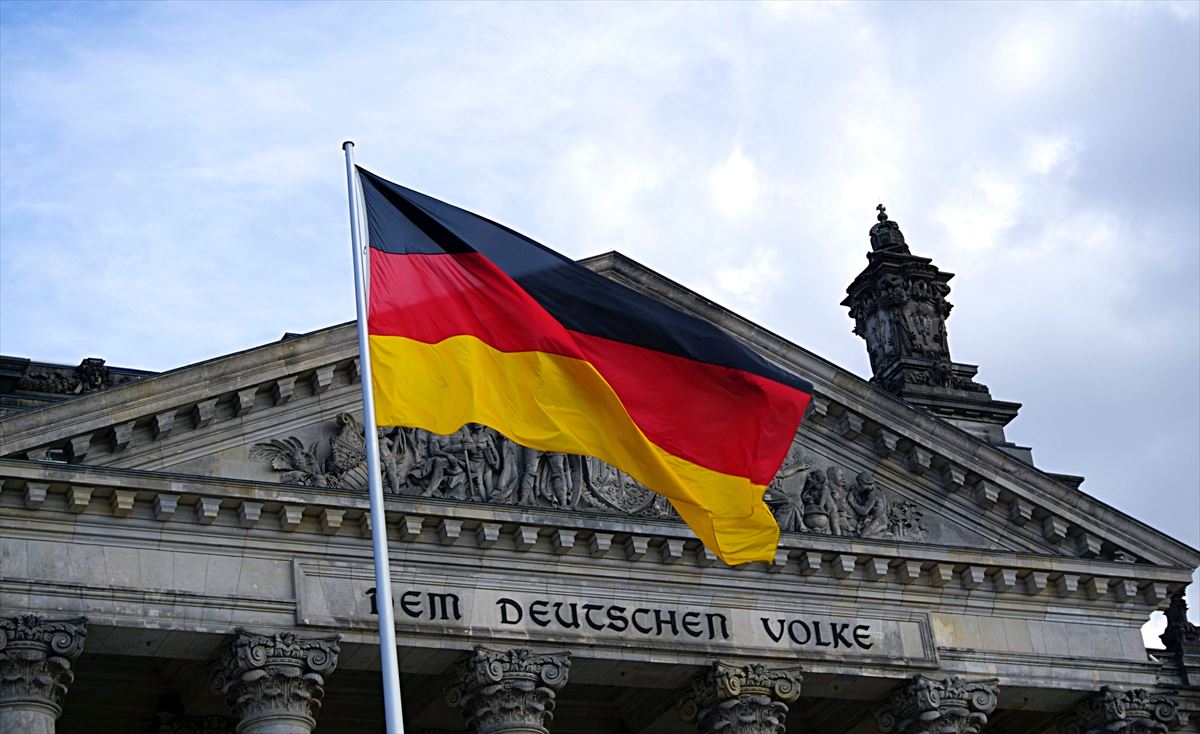 Bandera de Alemania frente a la fachada del Parlamento alemán
