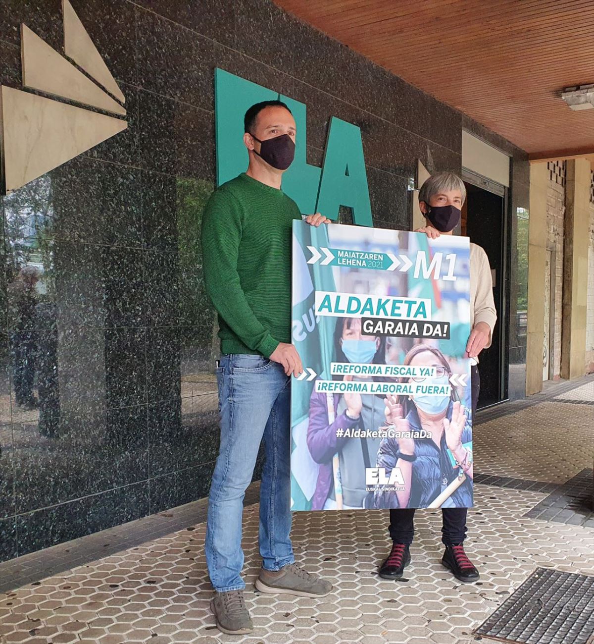 Mitxel Lakuntza y Amaia Muñoa junto al cartel del 1 de mayo