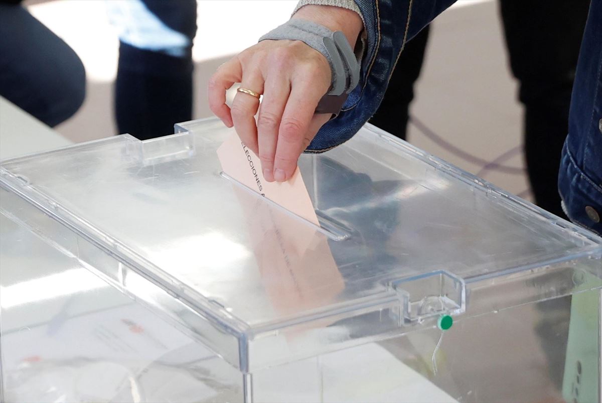 Una persona depositando su voto en una urna. 