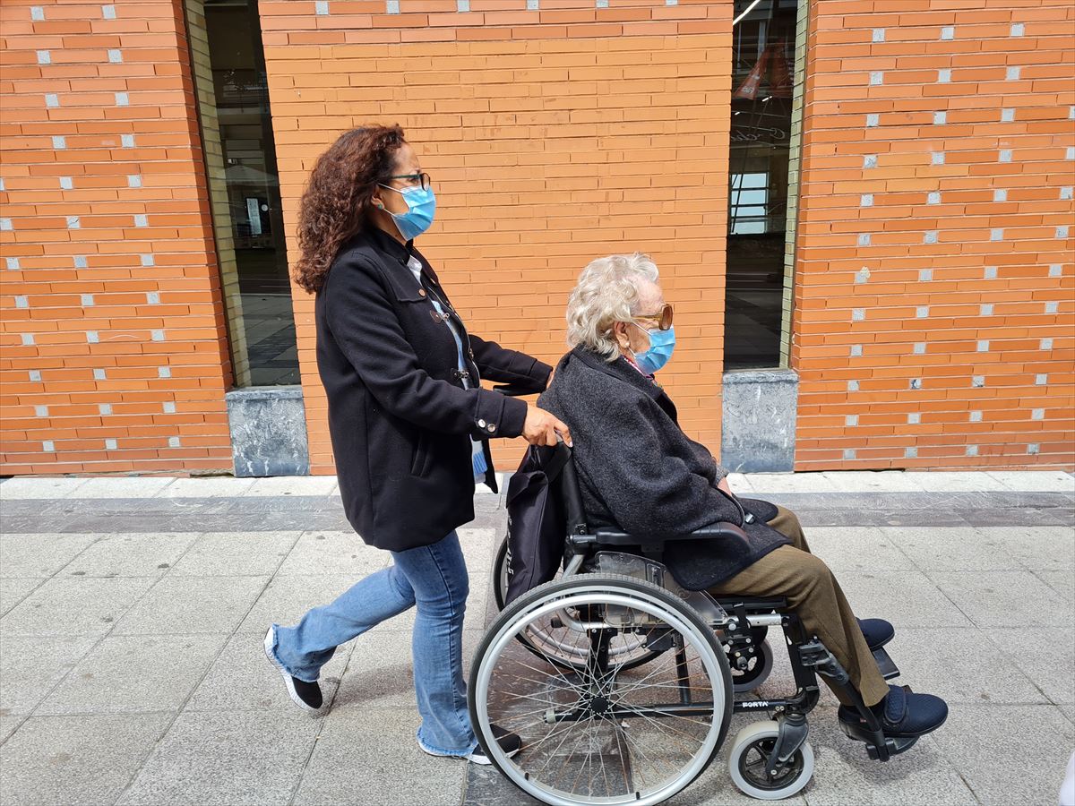 Una mujer empuja una silla de ruedas
