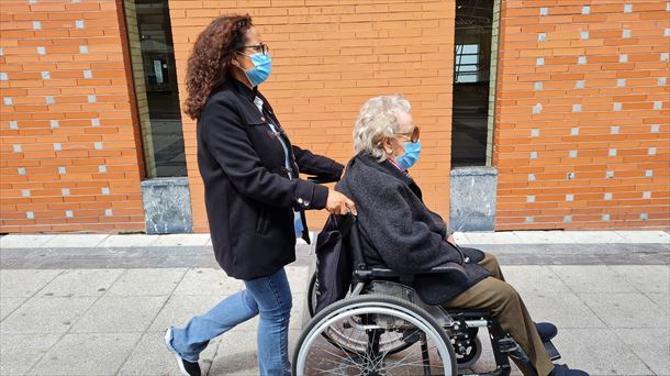 Una mujer empuja una silla de ruedas