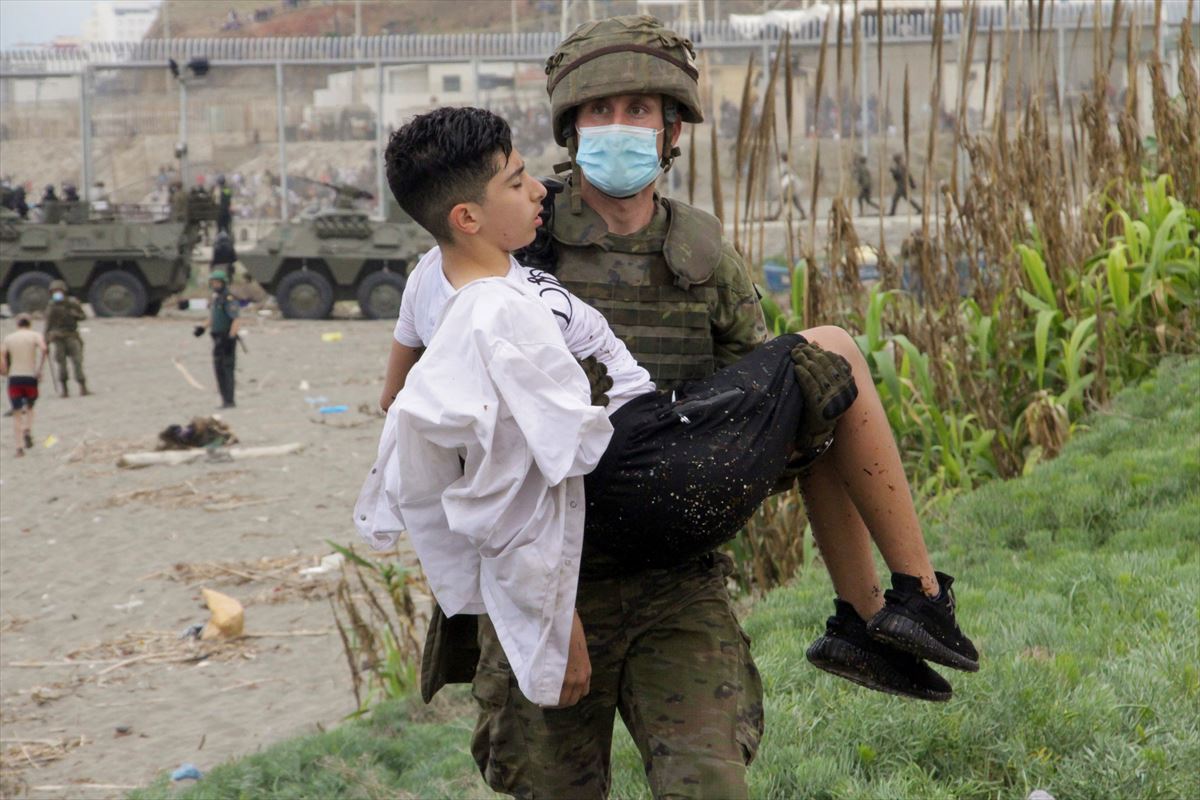 Un militar traslada en brazo a un menor migrante en Ceuta.
