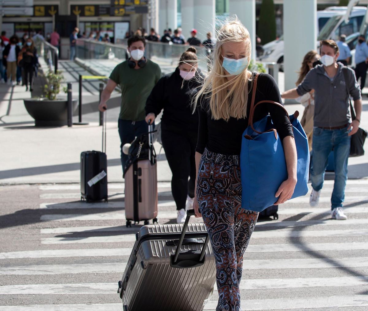 Viajeros con sus maletas en una pista de aeropuerto