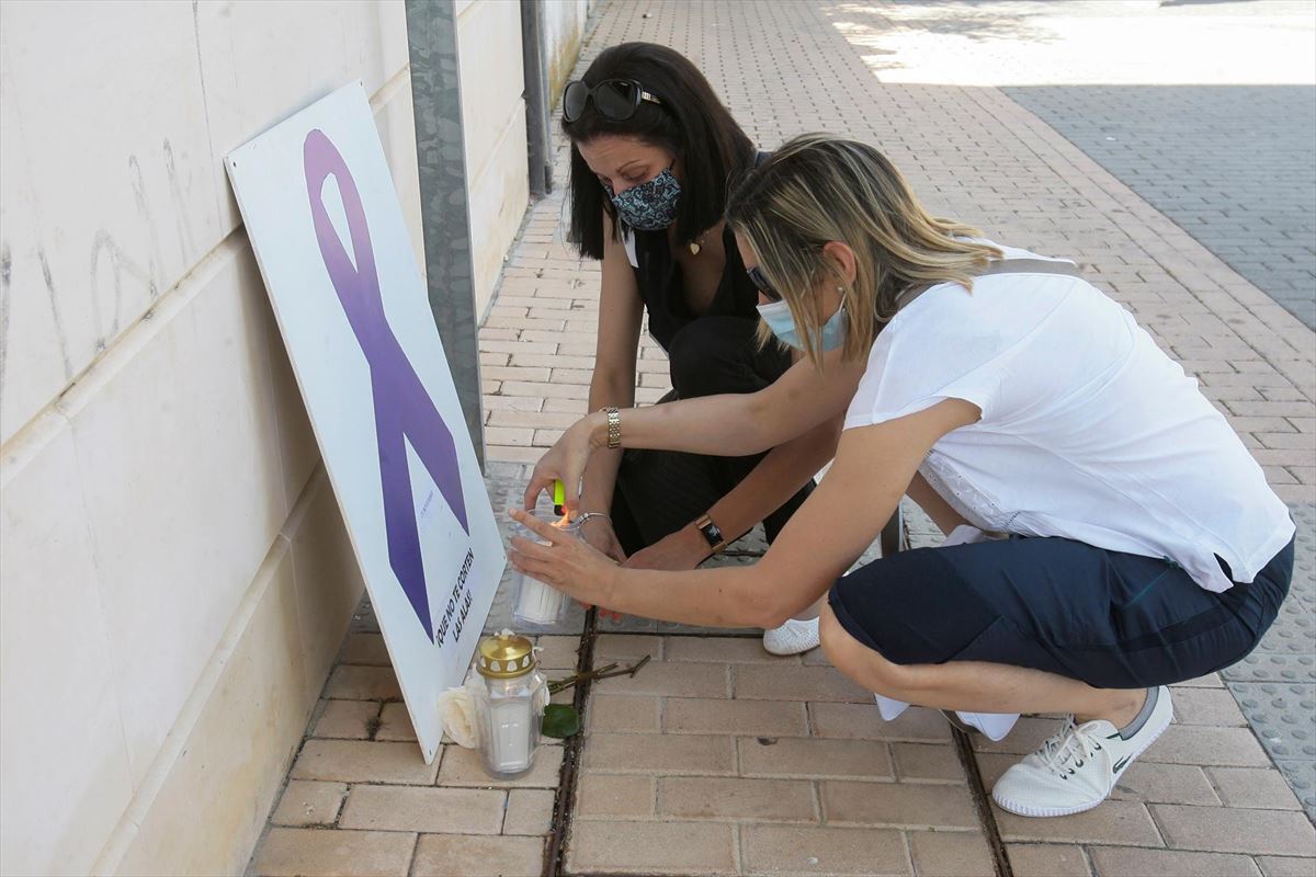 Dos mujeres depositan sendas velas en recuerdo de la mujer asesinada. Foto: EFE