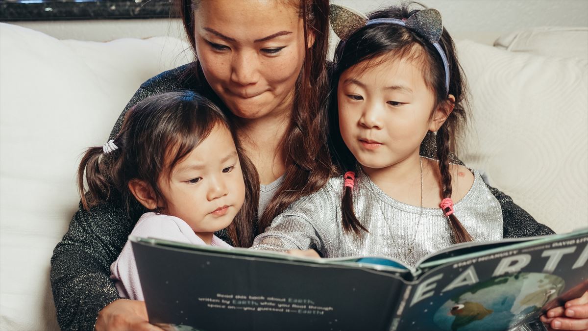 Dos niñas y una mujer chinas leen un cuento