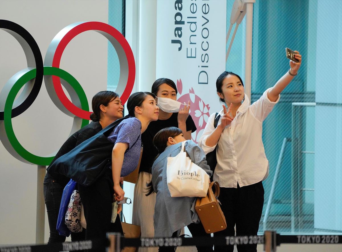 Varias personas fotografiándose frente al logo de los Juegos. 