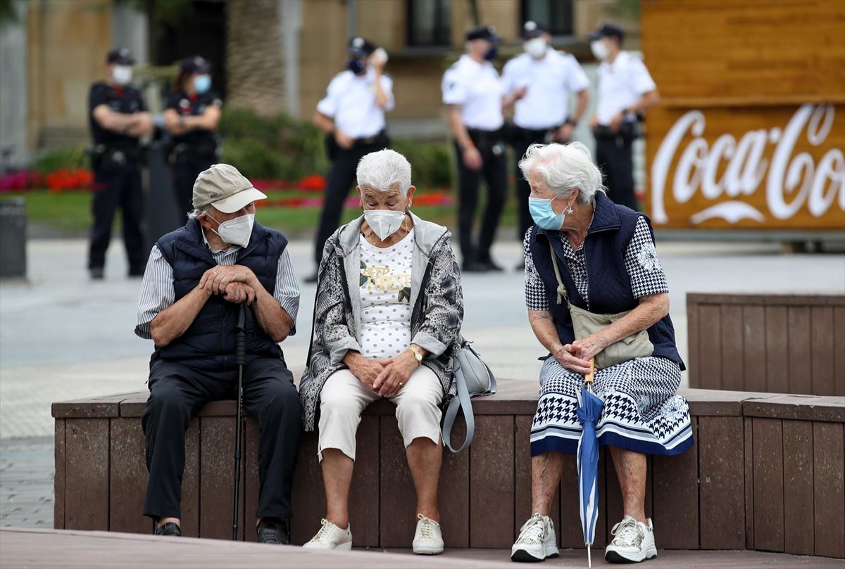 Tres persona mayores, con mascarilla, sentadas en un banco en Donostia. Foto: EFE
