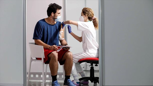 Una sanitaria vacunando a un joven. Foto: EFE