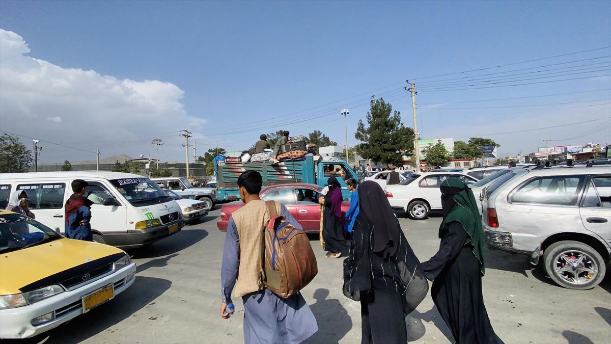 Varias y varios ciudadanos afganos, en el exterior del aeropuerto de Kabul