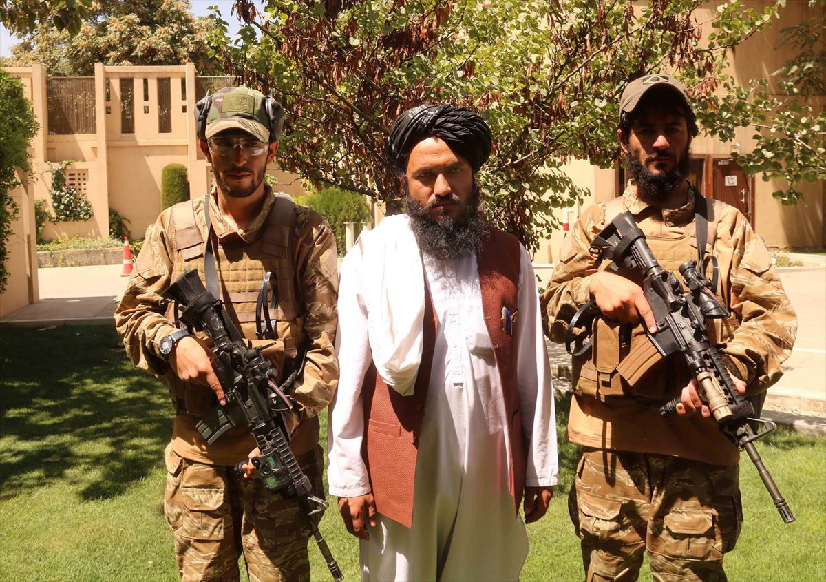 El portavoz de los talibanes, Zabiullah Mujahid, escoltado por dos militares. Foto: EFE 