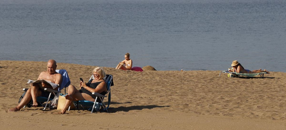 Varias personas disfrutan del buen tiempo en la playa de Ereaga (Bizkaia). 
