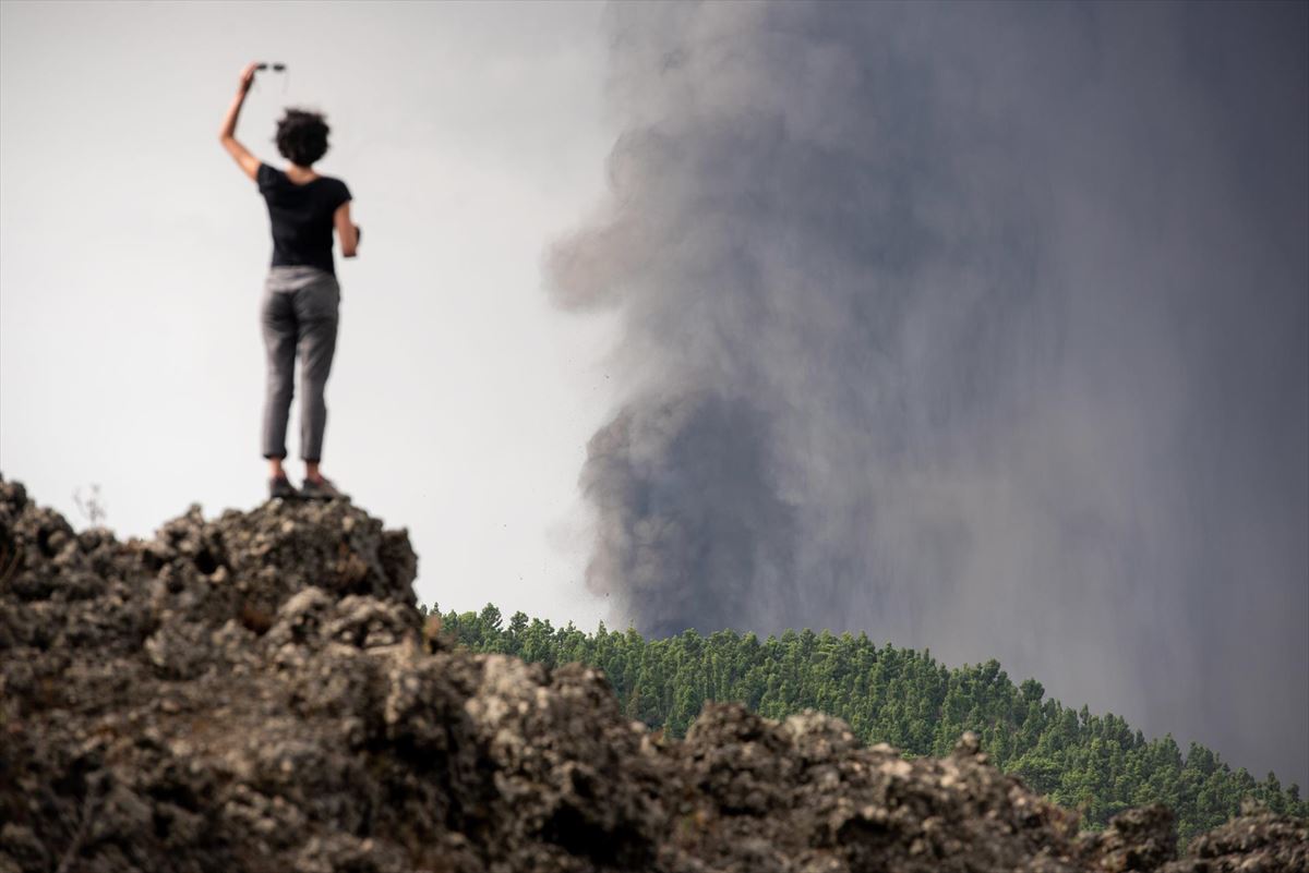 Una mujer observa la erupción desde la lejanía. Foto: EFE.