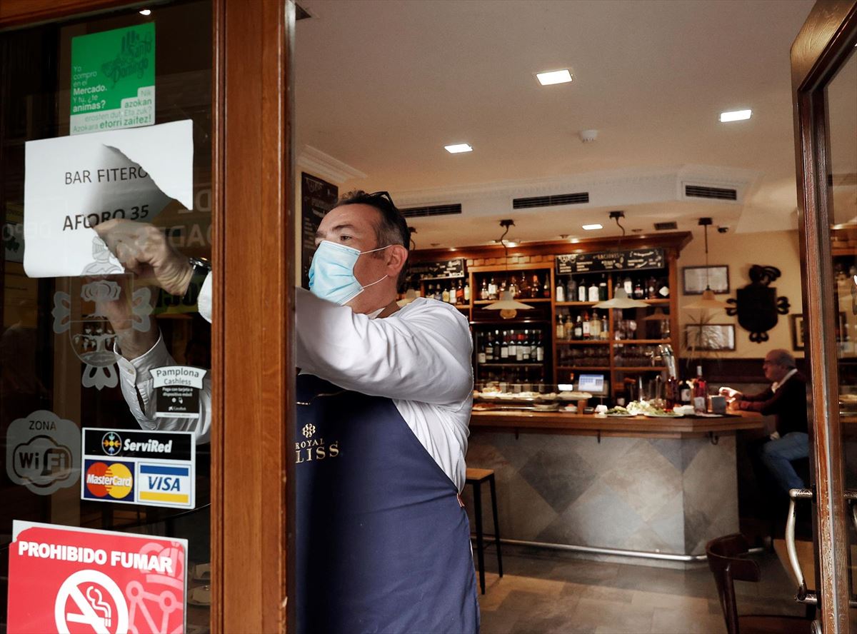 Un hostelero retira el cartel de aforo en un bar en Pamplona. EFE