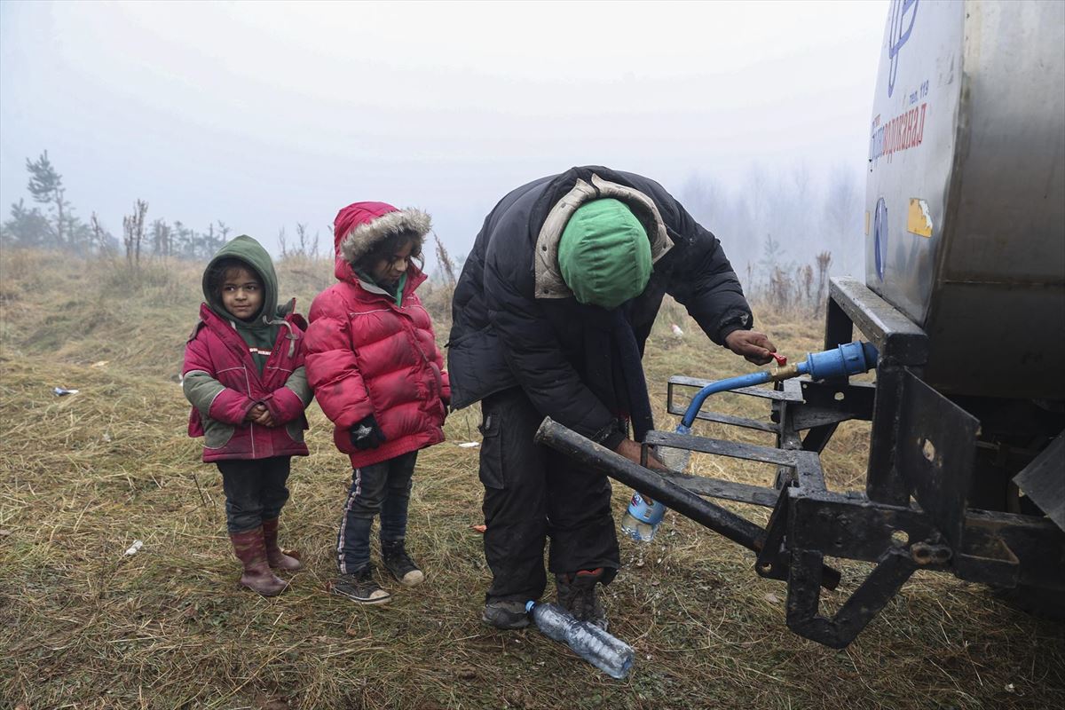 Una mujer recoge agua junto con sus hijos en la frontera de Bielorrusia. 