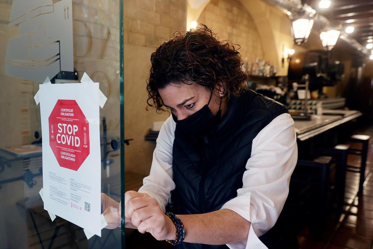 Una hostelera coloca un cartel sobre el pasaporte en su establecimiento de Valencia. 