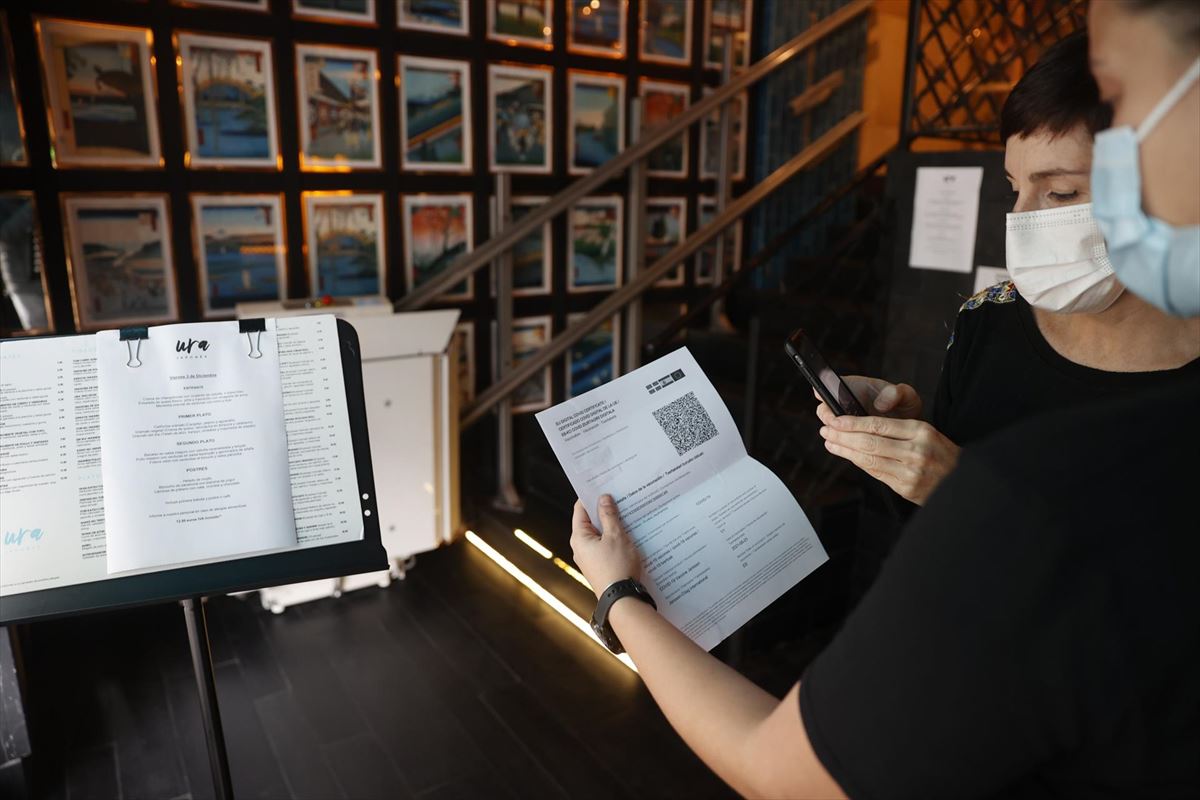 Una cliente enseña su pasaporte covid en un restaurante de Bilbao